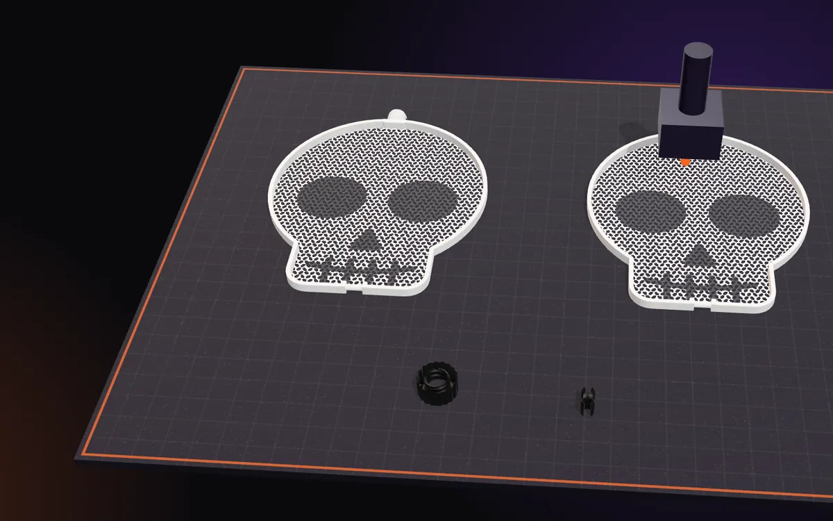 The two flat mesh halves of a skull on the build plate, with the nut and the clip